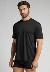 Černé tričko s krátkým rukávem vyrobené z hladké, lehké látky, s kulatým výstřihem a volnějším střihem, doplněné o černé šortky.