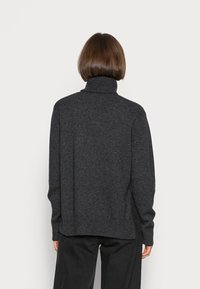 Pull à col roulé gris foncé en tissu tricoté, présentant une coupe décontractée, des poignets et un ourlet côtelés, avec une texture unie.