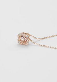 Collier en or rose avec un gemme rose entouré de cristaux transparents, une chaîne délicate et des détails raffinés sur le pendentif.