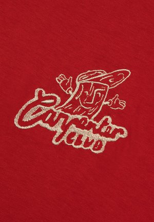 Roter Stoff mit besticktem grafischem Motiv in Creme, das einen Charakter mit ausgebreiteten Armen und dem Text "California Club" zeigt.