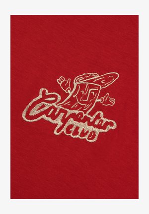 Roter Stoff mit besticktem grafischem Motiv in Creme, das einen Charakter mit ausgebreiteten Armen und dem Text "California Club" zeigt.