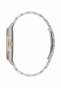 Vedere laterală a unei ceas cu carcasă din metal argintiu, având coroana aurie și o bratara metalică legată, evidențiind profilul său subțire și mecanismul de închidere.