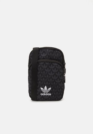 Sac bandoulière noir Adidas avec motif trèfle répétitif, poche avant zippée, logo trèfle blanc Adidas et sangle noire réglable.