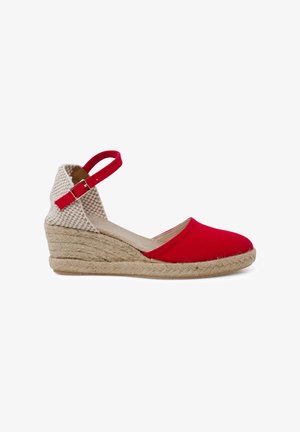 Red canvas wedge espadrille with a textured beige ankle strap and jute sole, featuring a closed toe and a rounded shape.