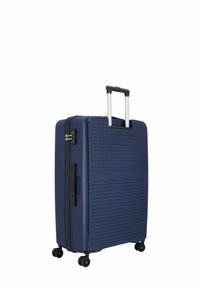 Valigia rigida blu navy con superficie texture, due ruote nere, manico estensibile e chiusura con zip. Presenta una maniglia laterale per il trasporto.