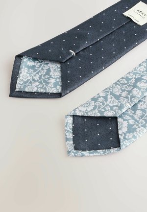 Marineblauer Krawatte mit kleinen weißen Punkten, ausgestattet mit einem blumigen, hellblauen Futter. Glatte Textur, scharfe Kanten und gut genäht.