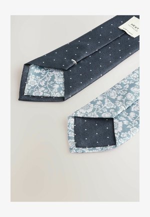 Jūras zilas krāsas kaklasaites ar maziem baltiem punktiņiem, ar ziedu raksta gaiši zilu odere. Gluda tekstūra, asas malas un labi izšūta.