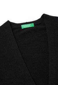 Czarny kardigan wykonany z dzianiny, charakteryzujący się dekoltem w serek. Metka z napisem "United Colors of Benetton" na zielonym tle.