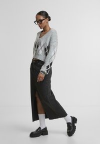 Siv krojen pulover z diamantnim vzorcem, v kombinaciji s črno denim maxi krilo z sprednjim razporkom. Obut s črnimi platform skrbeli in belimi nogavicami.