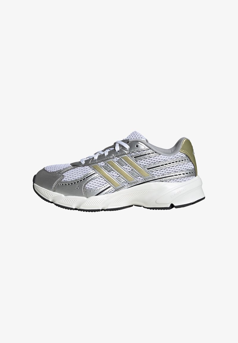 Chaussure de sport blanche et argentée en mesh avec des bandes doré clair, semelle blanche et semelle noire, vue de côté extérieur.