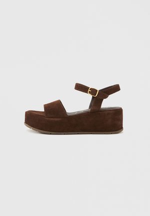 Brown suede platform sandals with a padded strap across the toe, ankle strap with a gold buckle, and a textured sole.