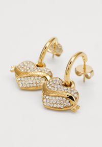 Kuldtooni kõrvarõngad südamekujuliste disainidega, kaunistatud selgete rhinestones'itega ning väikeste detailidega, mis rõhutavad luige motiivi.