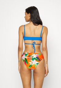 Top de bikini azul com alças ajustáveis e parte de baixo de cintura alta com estampa floral colorida, apresentando tons de laranja, rosa e verde.