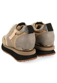 Zapatillas deportivas para mujer en beige y gris, con un cuello acolchado, lados texturizados, acentos metálicos y una suela de goma negra elevada.