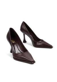 Ciemnoczerwone skórzane szpilki z wąskim noskiem, eleganckim designem i unikalnym, skośnym kształtem obcasa. Gładka tekstura, minimalna ilość dodatków.