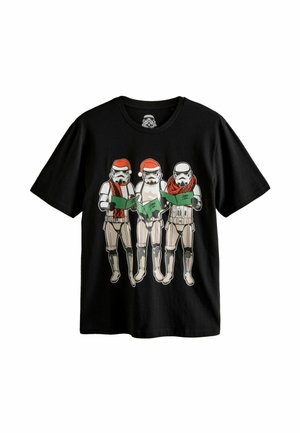 Juodas marškinėliai su trimis Stormtrooperiais, dėvinčiais Kalėdų Senelio skrybėles ir raudonas šalikas, laikantys žalius dainų sąsiuvinius, su ryškiu grafiniu dizainu.