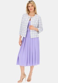 Jasnoniebieska i biała marynarka w kratkę z rękawami do łokcia, w połączeniu z plisowaną lawendową sukienką. Beżowe sandały na obcasie dopełniają całość.