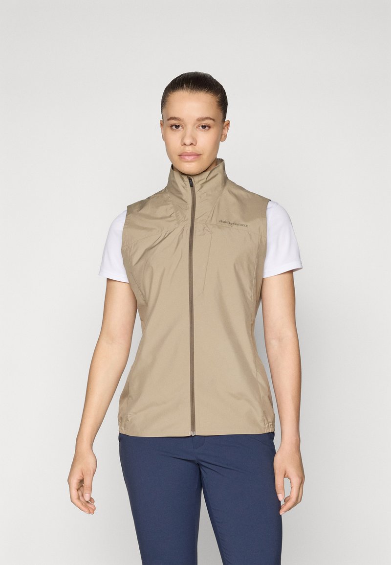 Lightweight, sleeveless, beige vest with a high collar and full front zipper. Made of smooth fabric with subtle branding on the shoulder.