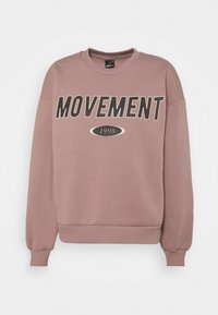 Bawełniany sweter w kolorze mauve z grafiką "RUCH" i "1998" w kolorze czarnym, z okrągłym dekoltem i ściągaczami przy rękawach.