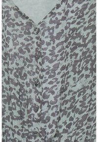 Světle šedá blůza s leopardím vzorem v tmavších šedých tónech. Design do V s knoflíkovými uzávěry vpředu.