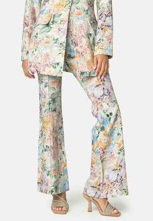 Traje de pantalón con estampado floral, con pantalones de pierna ancha y blazer a juego, combinado con sandalias beige de tacón alto y tiras.