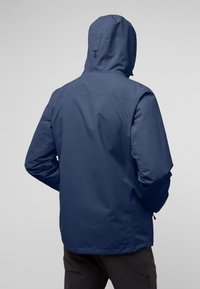 Giacca impermeabile blu navy con cappuccio, presenta una texture liscia e un design minimalista, mostrata dal retro con un taglio dritto.