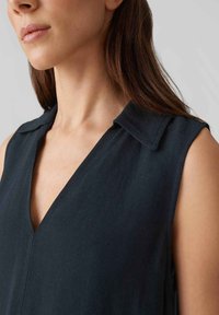 Dark sleeveless blouse featuring a V-neckline and a collar. Made of lightweight fabric with a subtle texture and clean lines.