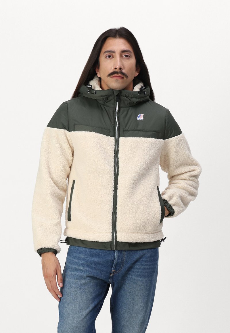Giacca in pile con corpo crema e pannelli verde scuro. Presenta un cappuccio, zip frontale e polsini elasticizzati. Patch con logo sul petto. Vestibilità casual.