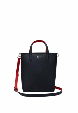 Sac fourre-tout en cuir noir avec poignées intérieures rouges et bandoulière détachable rouge et noire, orné d'un logo crocodile argenté.