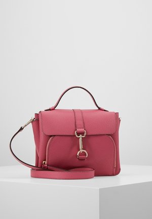 Sac à main en cuir rose avec poignée supérieure, rabat avant sécurisé par une fermeture dorée, et bandoulière réglable reposant sur un piédestal blanc.