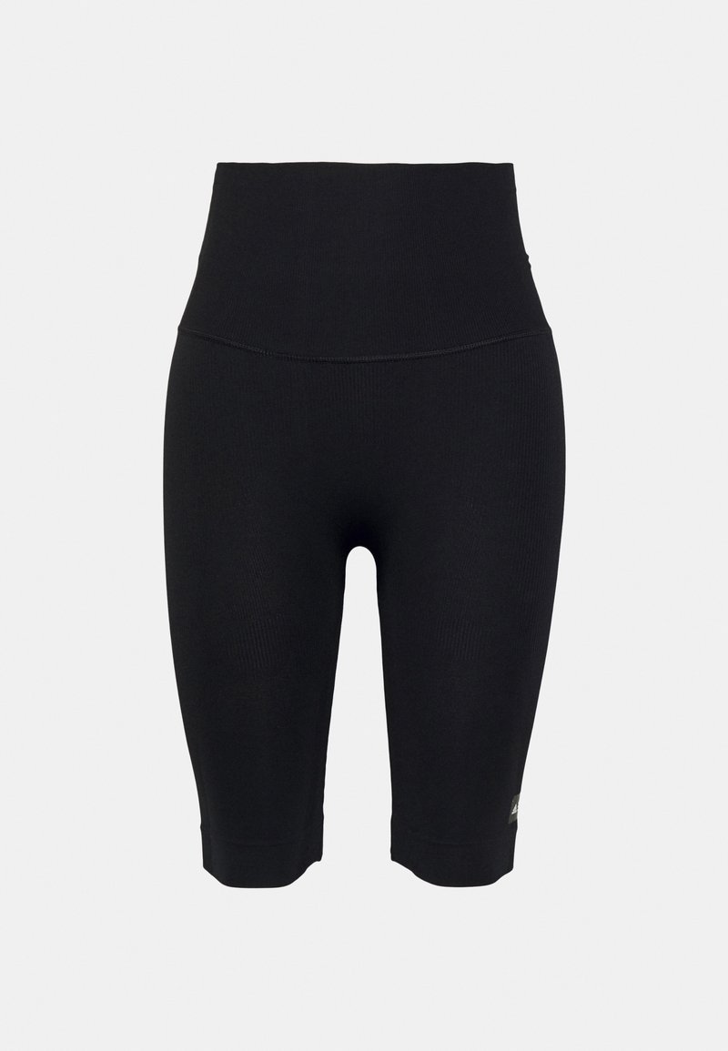 Short cycliste noir taille haute sans couture, longueur mi-cuisse et petit logo réfléchissant près de l'ourlet sur fond uni.