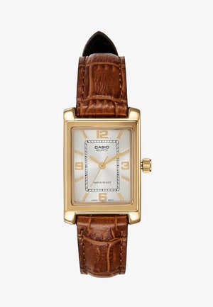 Montre-bracelet rectangulaire Casio quartz dorée avec cadran blanc, index dorés et bracelet en cuir marron texturé.