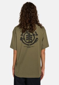 Oliven grøn bomulds t-shirt med korte ærmer. Stort sort grafisk design med værktøj og tekst på ryggen. Løs pasform med en glat tekstur.