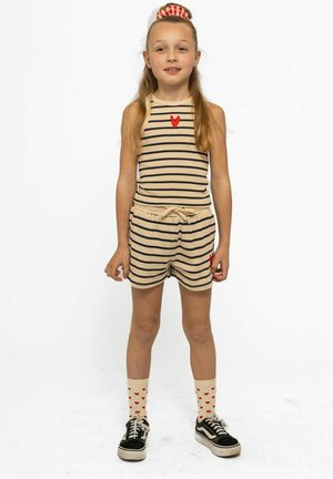 Gestreepte beige mouwloze top met een rode hart, bijpassende shorts en kniehoge sokken met rode harten. Zwarte sneakers maken de outfit compleet.