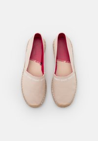 Espadrilles en toile beige clair avec doublure intérieure rose, semelle en jute tissée beige et logo "TOMMY JEANS" en blanc sur le dessus.