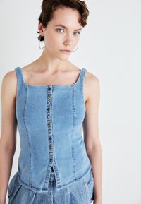 Lichtblauw denim top met een vierkante halslijn, voorzien van een knopenlijst aan de voorkant, en een aansluitende pasvorm met naaddetails.