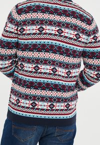 Knit sweater featuring a multi-colored geometric pattern in red, white, and blue on a navy background. Ribbed cuffs and hem.