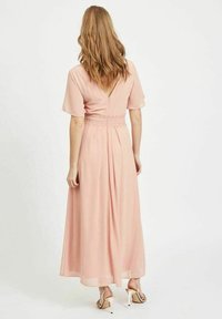 Robe longue rose avec des manches courtes et un dos en V. Présente une taille froncée avec une bande texturée. Tissu léger et fluide.