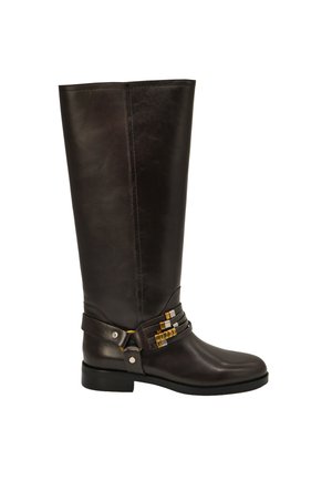 Bota alta de cuero negro con tacón bajo, correas decorativas y adornos metálicos alrededor del tobillo.