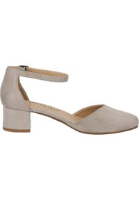 Zapato de tacón bloque con tira en el tobillo en ante beige claro. Cuenta con una punta redonda y un tacón corto y robusto. Diseño minimalista con una textura suave.
