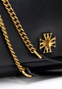 Sac en cuir texturé noir avec une bandoulière en chaîne dorée, présentant un emblème doré et un détail de fermoir.