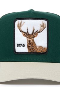 Zaļā cepure ar strukturētu dizainu, uz kuras ir balta izšūta plāksne ar stalta galvu virs vārda "STAG". Beigā rēķins un struktūras audums.