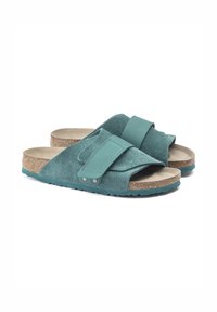 Teal ruskindssandaler med en bred rem og justerbar flap. Kork fodseng og struktureret gummisål giver komfort og greb.