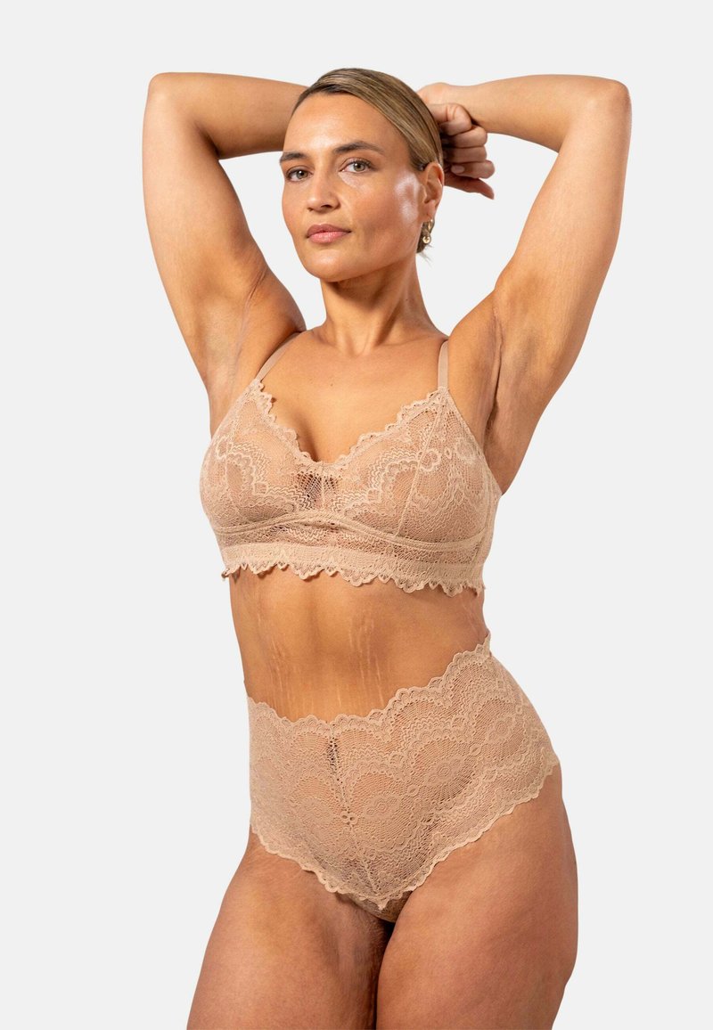 Spets-bh och högmidjade trosor i nude-färg med scalloperade kanter och intrikata blommönster. Justerbara remmar för komfort.