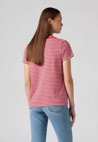 T-shirt à manches courtes rayé rouge et blanc, col rond, en coton doux, coupe standard, associé à un jean bleu clair.