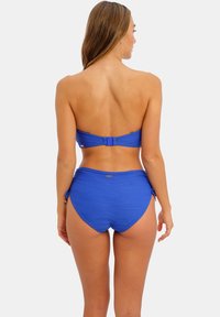 Costume da bagno blu a due pezzi che presenta un top senza spalline con gancio sul retro e un pantaloncino alto con lacci laterali regolabili e tessuto testurizzato.