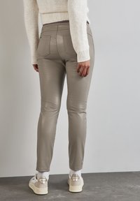 Grå byxor i konstläder med slim fit, femfickorsdesign och synliga sömnadsdetaljer. Bärs med vita och beige sneakers.