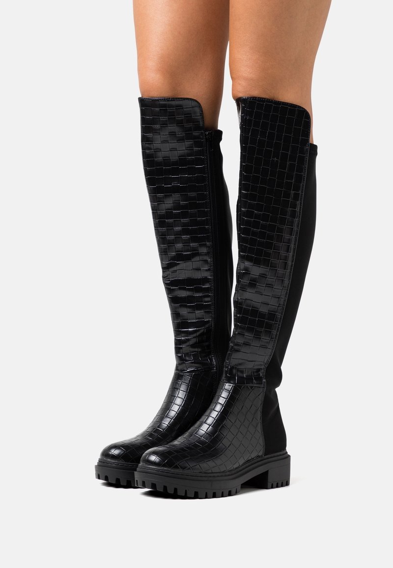 Bottes noires jusqu'aux genoux avec un design en relief crocodile, texture lisse, semelle épaisse, fermeture éclair sur le côté et un panneau en tissu contrastant.
