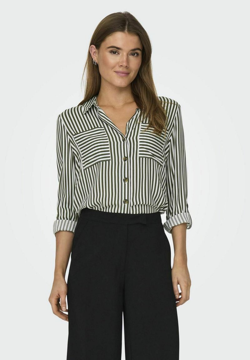 Gestreepte button-up shirt in groen en wit, met twee borstzakken, opgerolde mouwen en lichte stof. Gecombineerd met zwarte wijde broek.