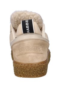 Scarpa in suede beige con suola marrone testurizzata e colletto foderato in lana, con la scritta "SHABBIES" in rilievo sul tallone e un occhiello nero con testo bianco.
